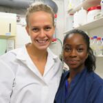 Photo of a scientist and a student from a minority ethnic background (both female) smiling together in a lab