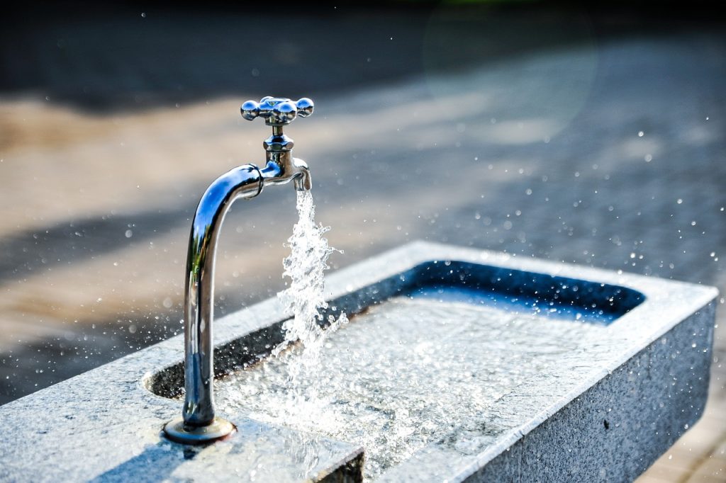 Water flowing from a tap into a basin that is nearly full