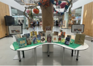 Picture of a stand in the library foyer, taken at the Lancelot Ribeiro retrospective by an IP & ME committee member. There are garlands above a table filled with relevant books and leaflets.