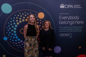 Photo of Kathryn Sayers and Victoria Barker standing in front of a CIPA banner